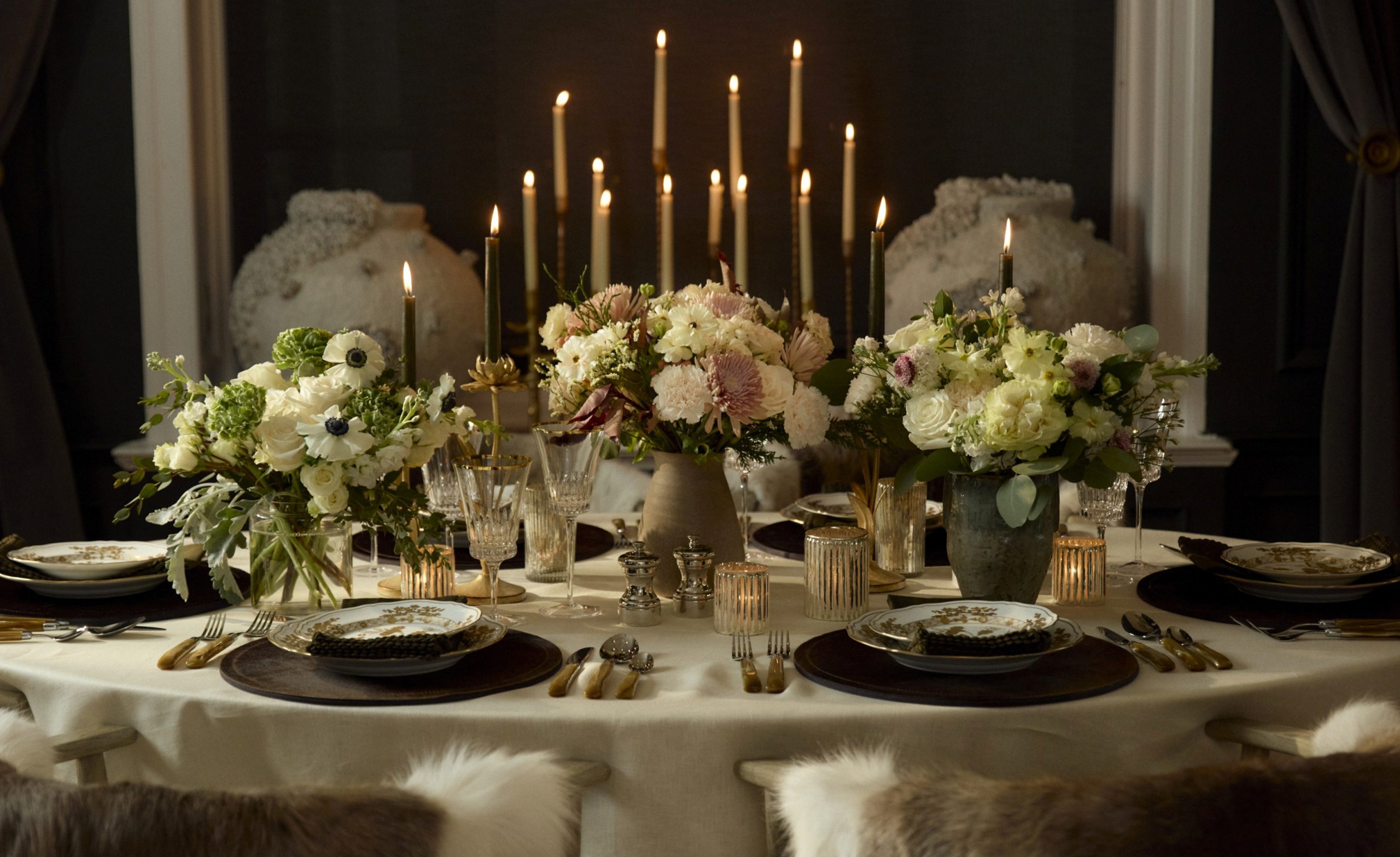 An oval dining room table topped with Kathy Kuo Home x UrbanStems floral bouquets