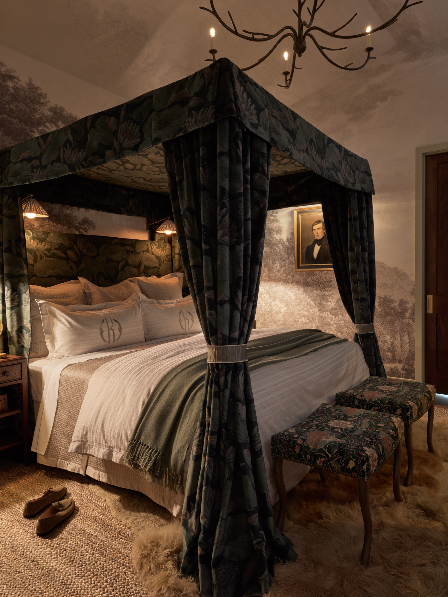 A cozy primary bedroom with a four-posted canopy bed, mural wallpaper, and Visual Comfort chandelier