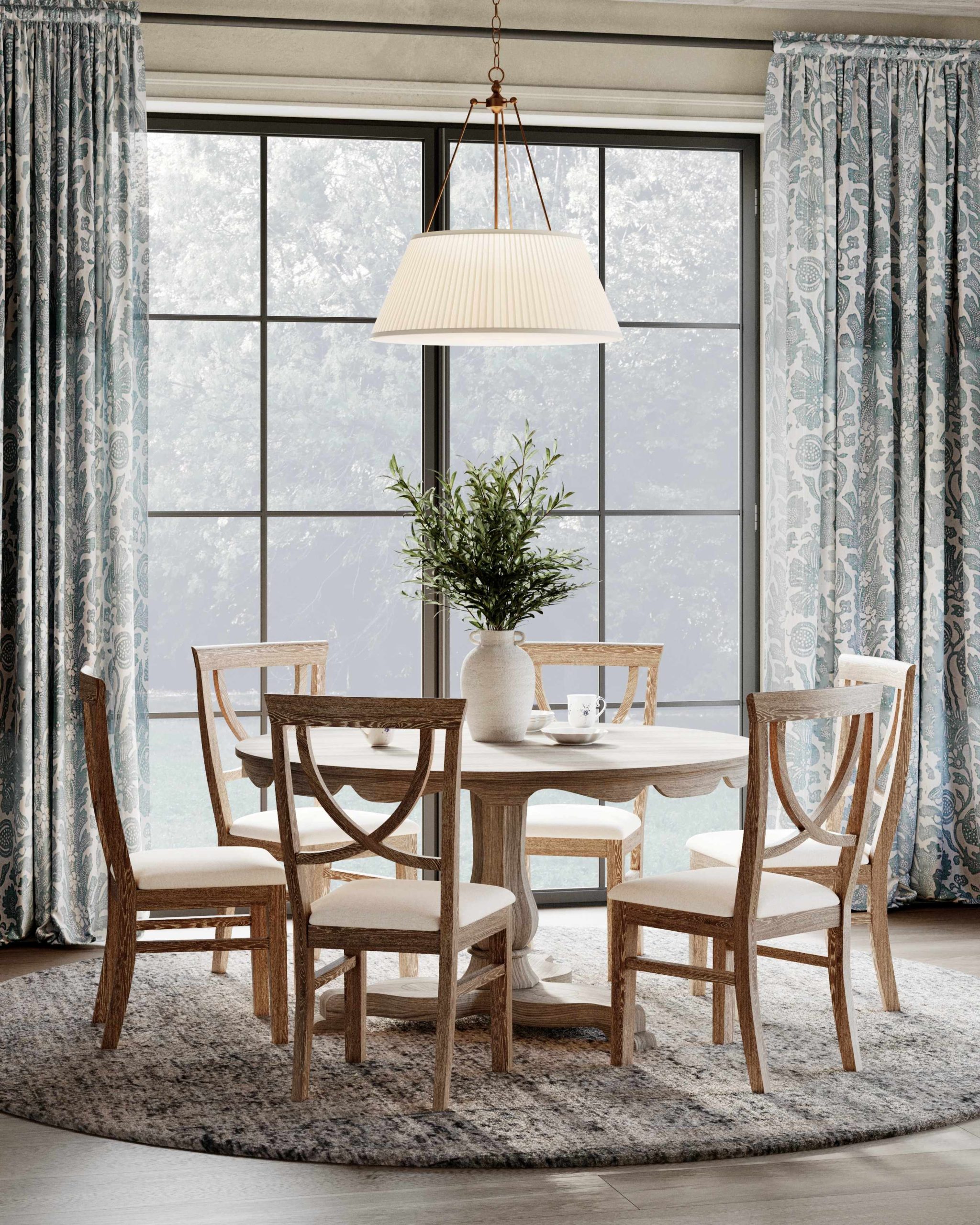 An English kitchen dining nook with a round oak table, oak dining chairs, a pendant light, and picture windows overlooking the countryside