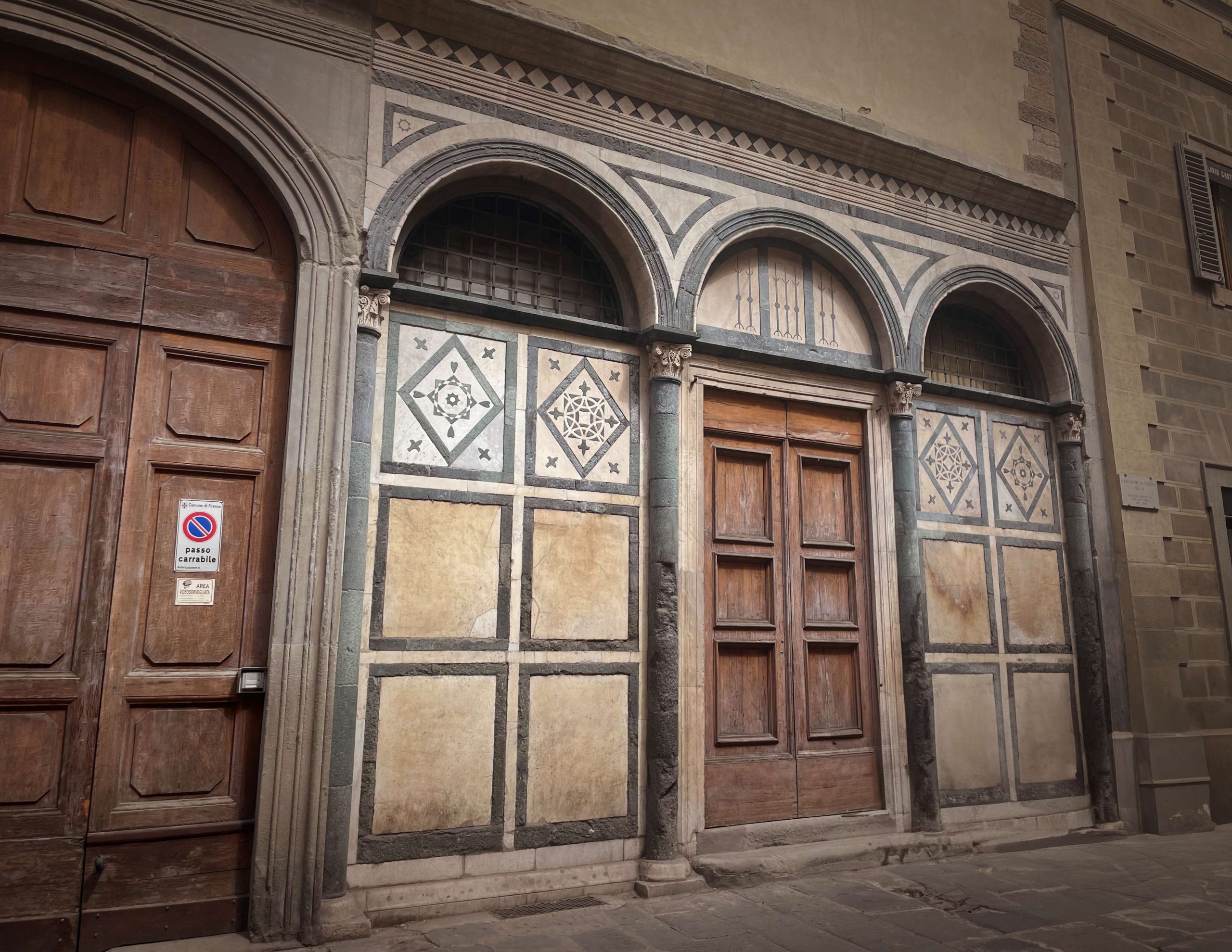 Arched wooden doorways on a quiet Florence street
