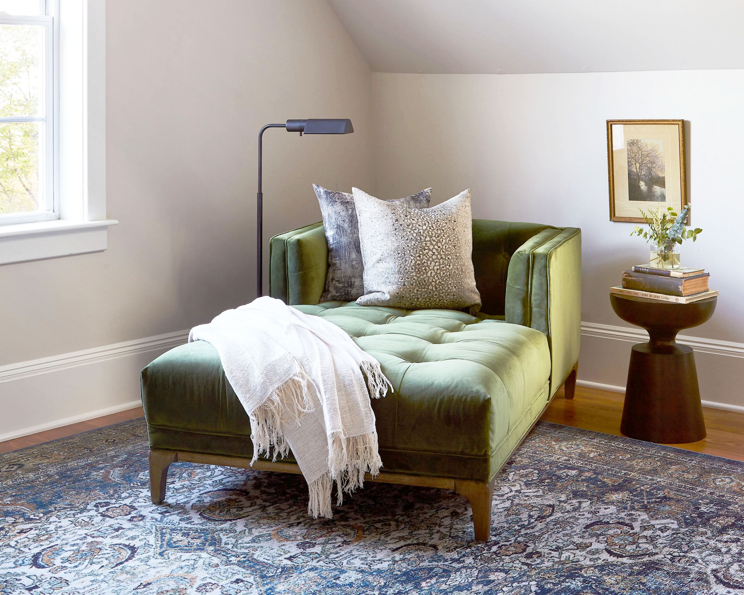 a green velvet tufted chaise lounge in a bedroom reading nook