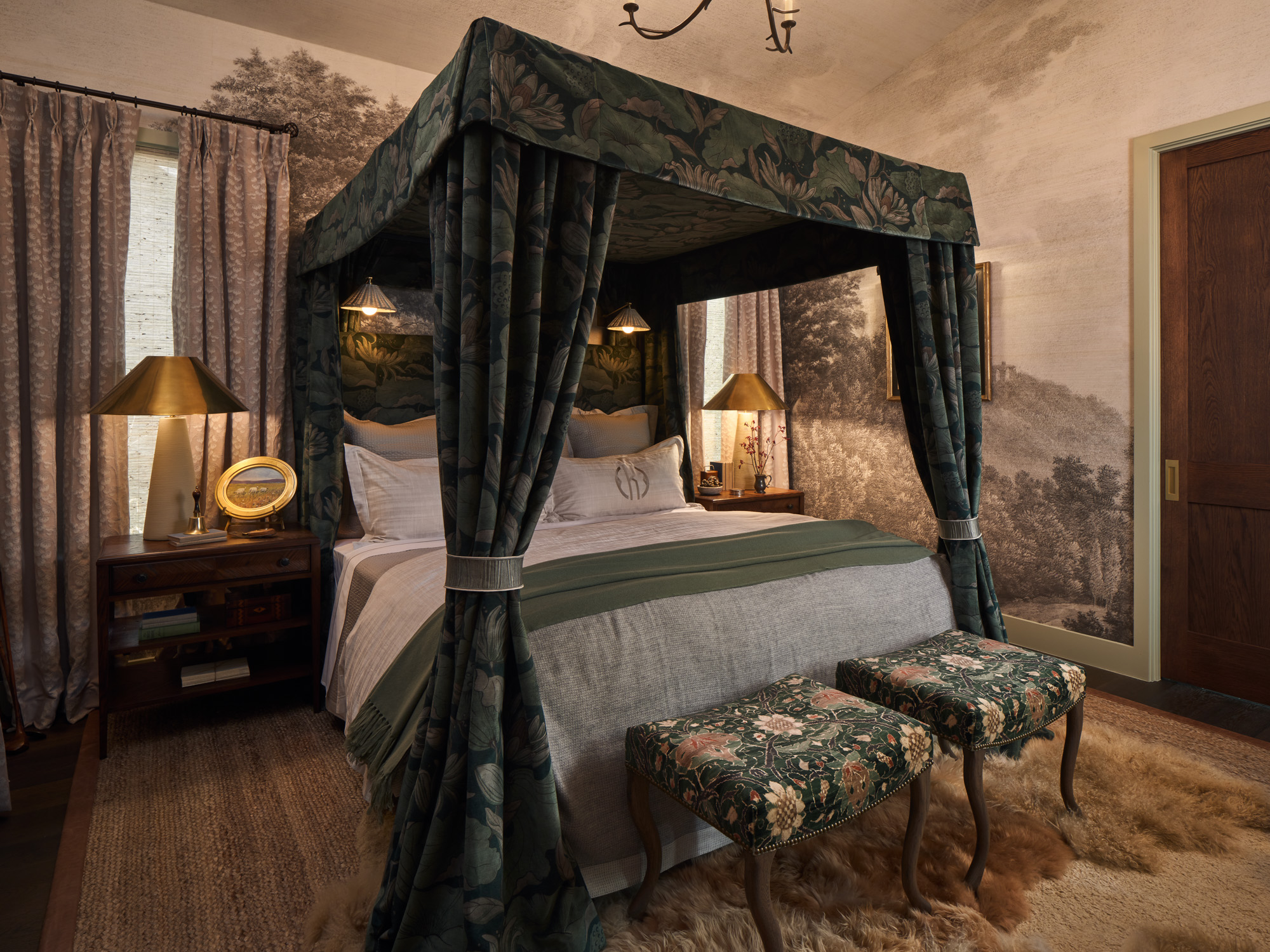 A cozy primary bedroom with a four-poster canopy bed, layered rugs, patterned ottomans, and soft, layered bedding