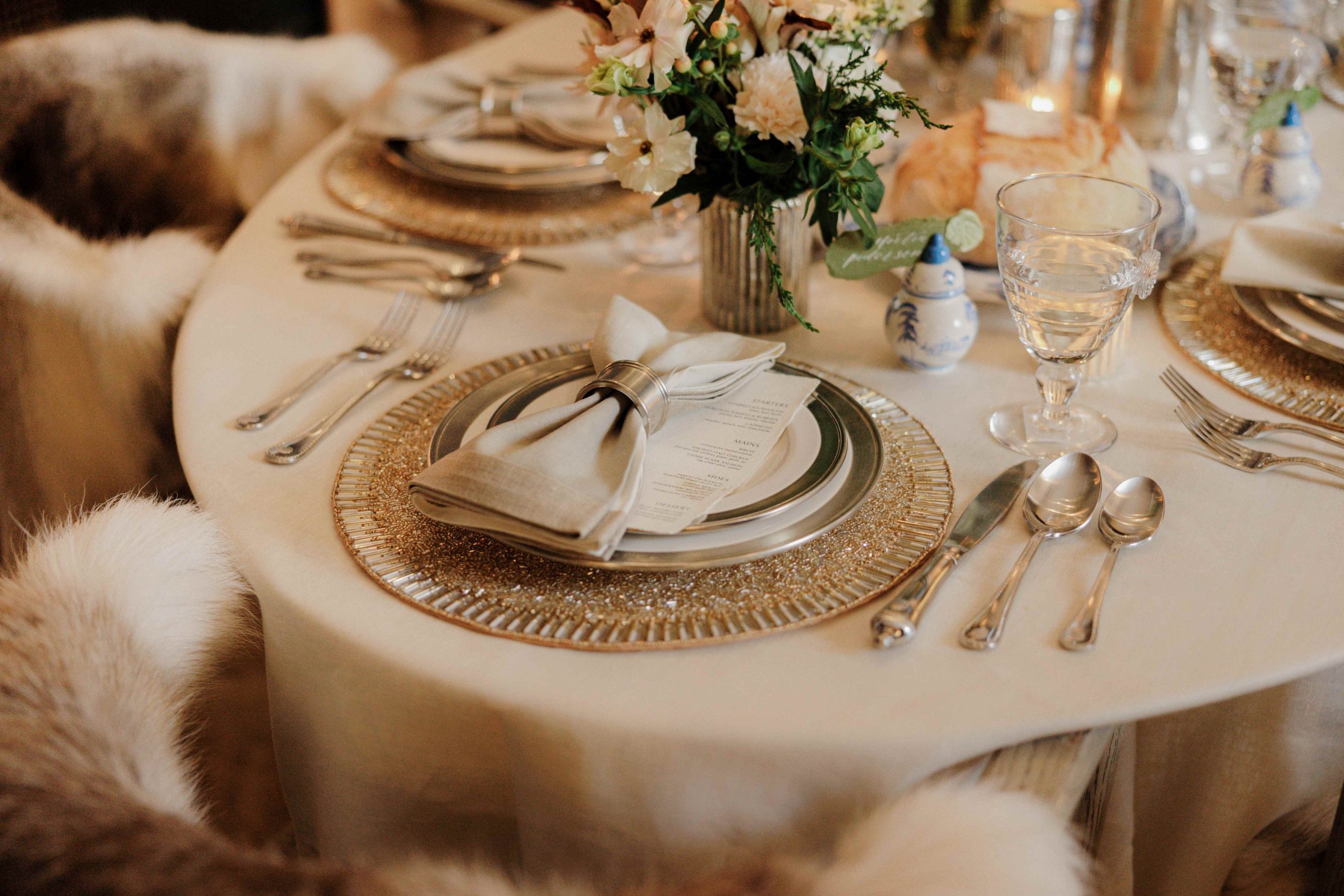 holiday tabletop with tapere candles, flowers, and white and silver dishware