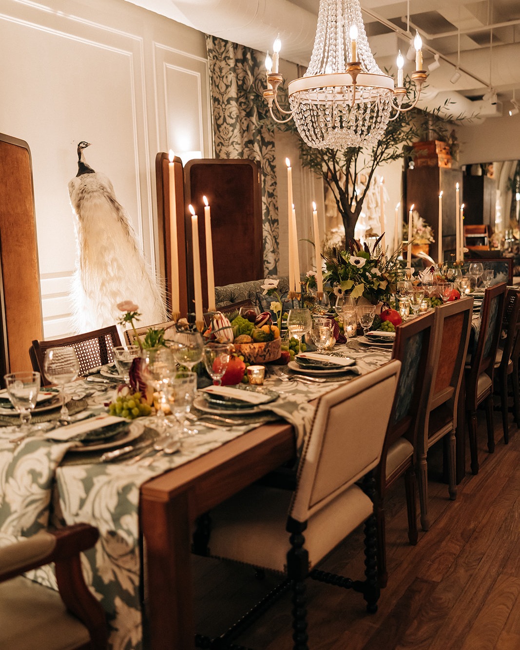 Layered place settings at a dinner table topped with floral arrangements and candelabras
