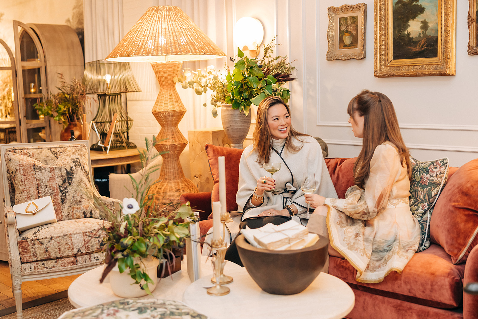 Kathy Kuo and Jenny Cipoletti sit on a velvet sofa at the Kathy Kuo Home Design Showroom