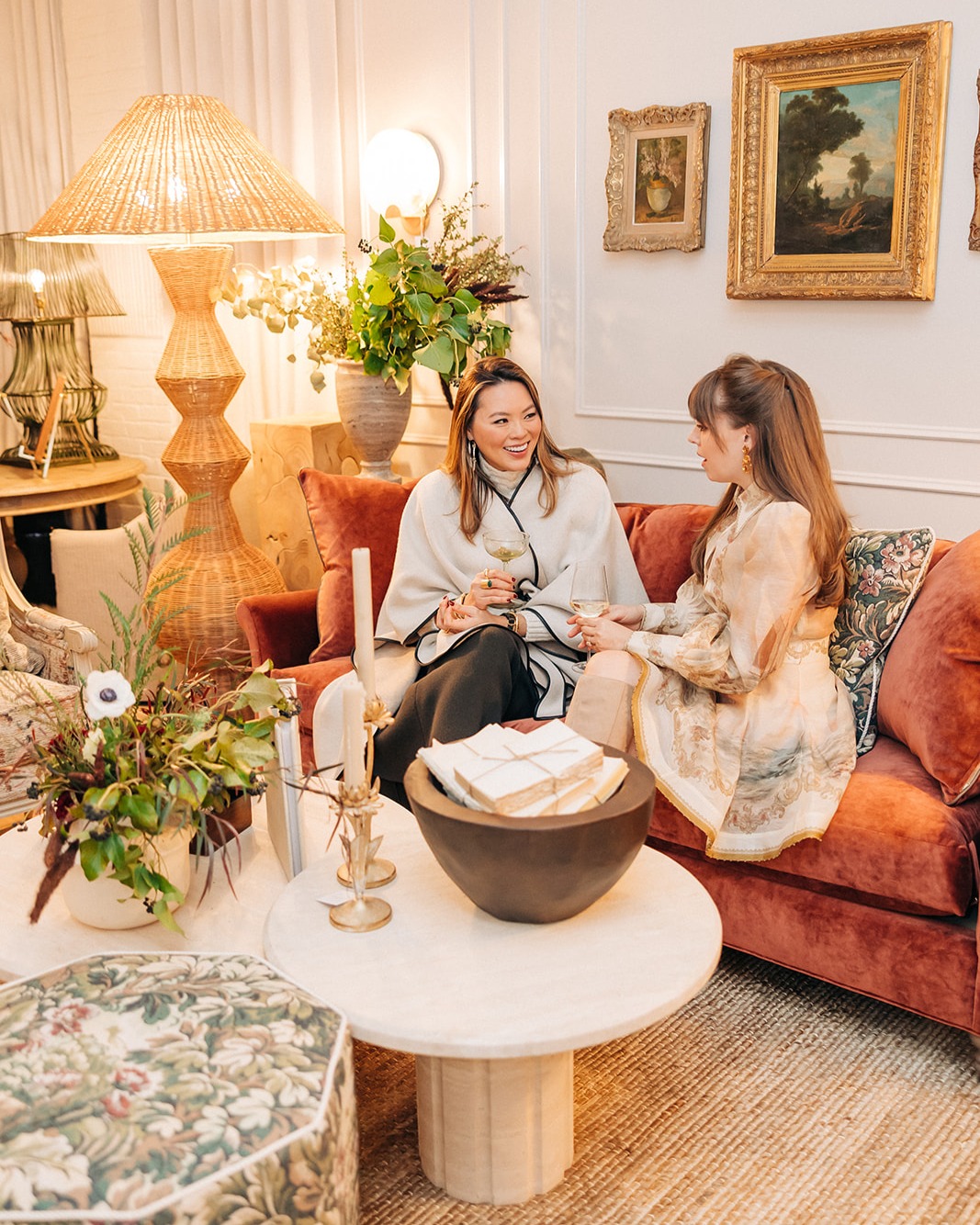 Kathy Kuo and Jenny Cipoletti sit on a velvet sofa at the Kathy Kuo Home Design Showroom