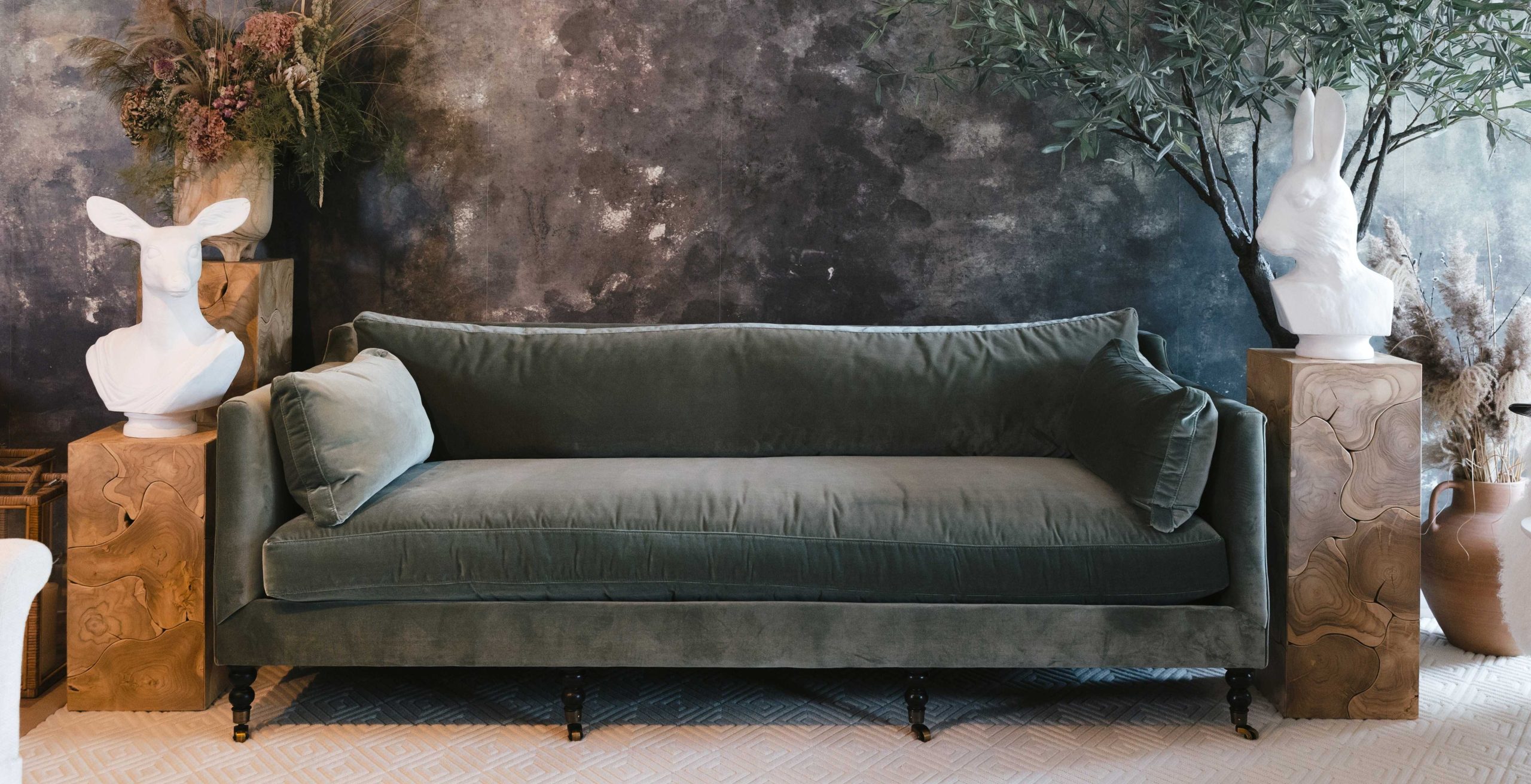 green velvet Madeline sofa with turned wood legs and antique brass casters