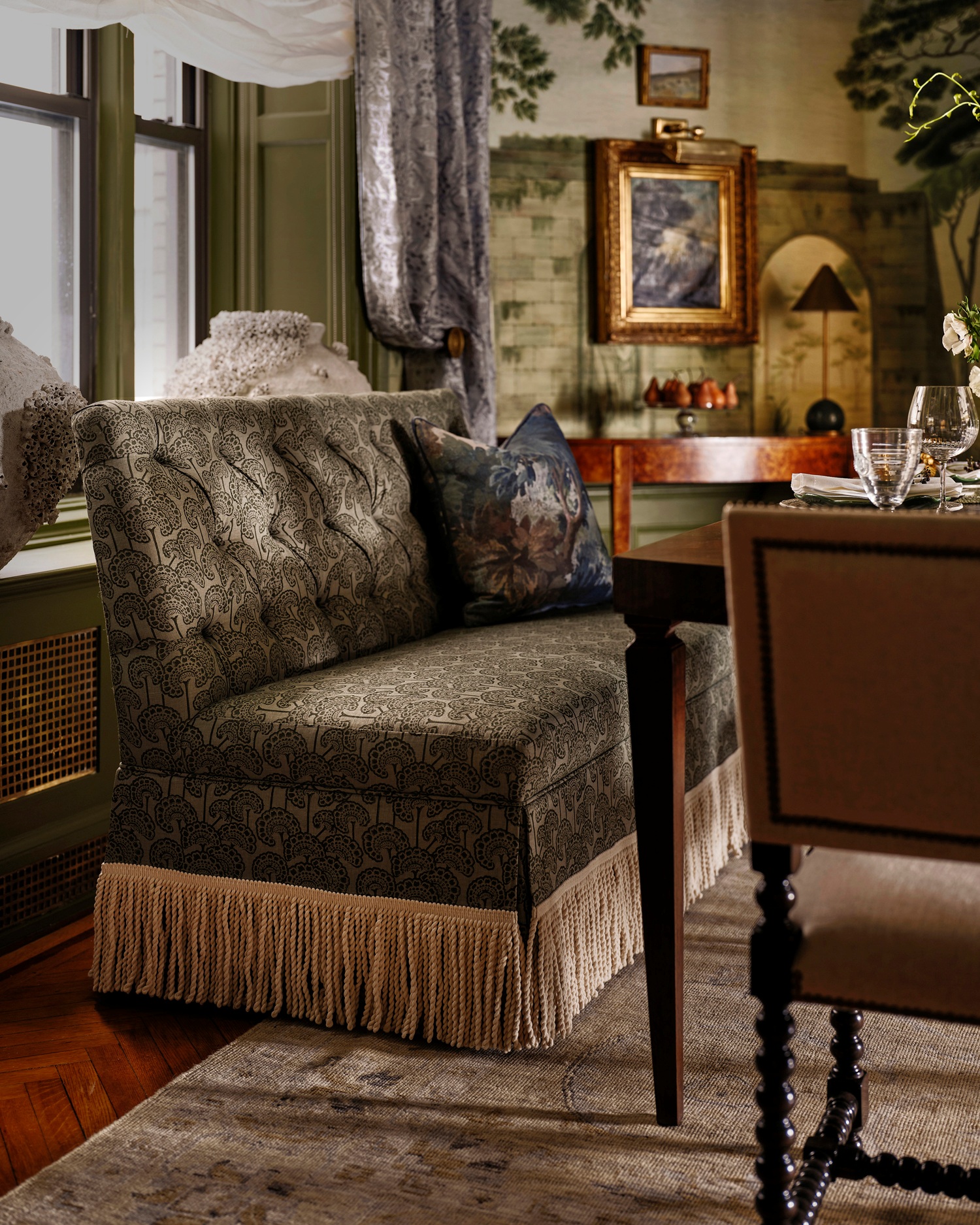 A green patterned banquette with fringe in a new york city apartment dining room