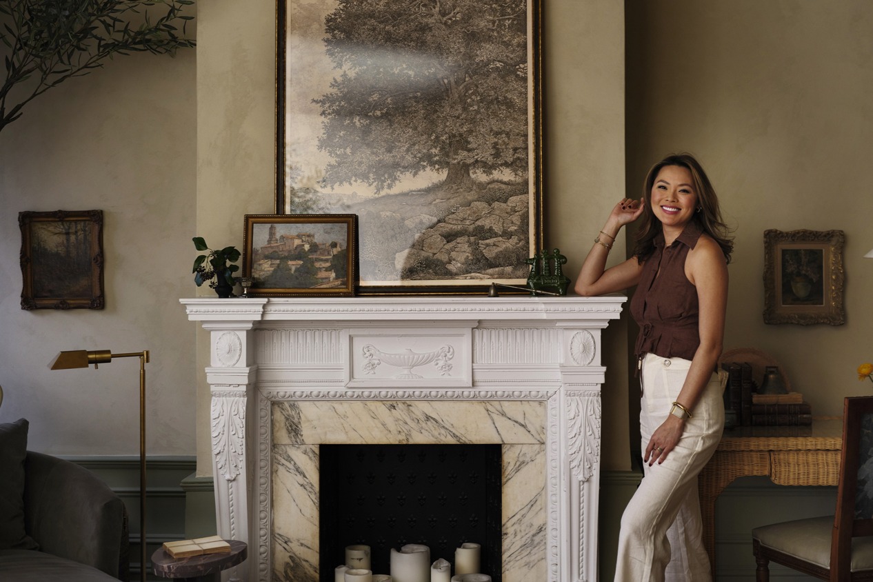 Kathy Kuo stands next to the marble and wood fireplace in her New York living room