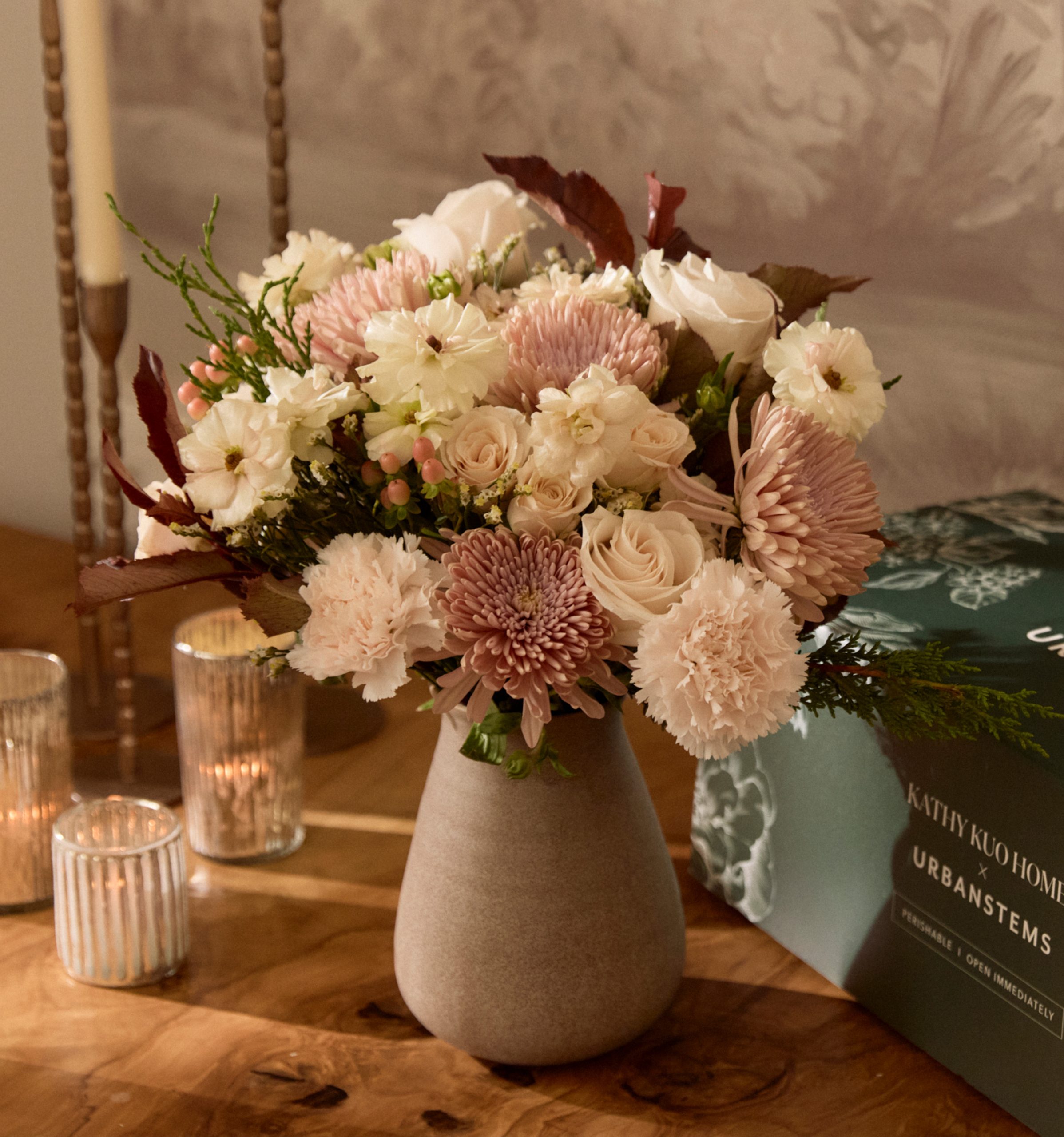 A Kathy Kuo Home x UrbanStems floral bouquet in a modern vase with spray roses, ranunculus and pink mums