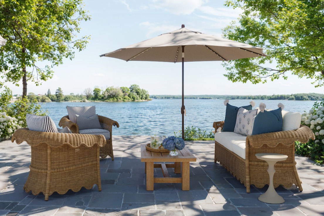 scalloped outdoor wicker furniture on a stone patio next to a lake