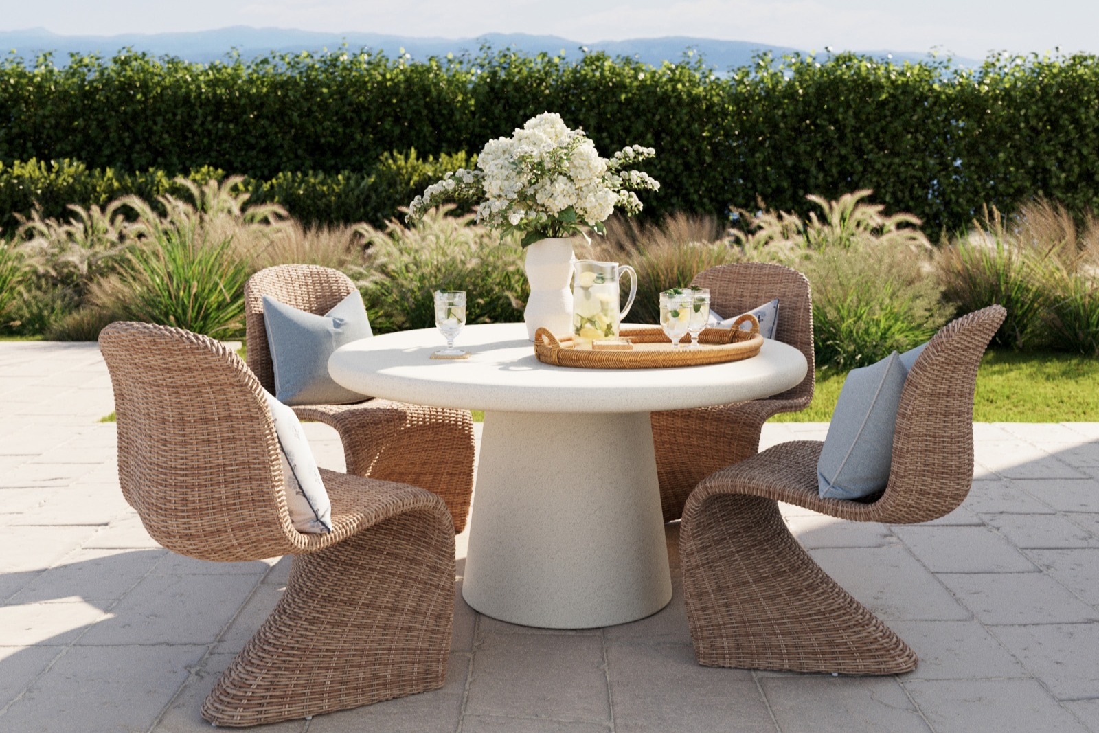 a round outdoor concrete dining table is surround by sculptural wicker dining chairs