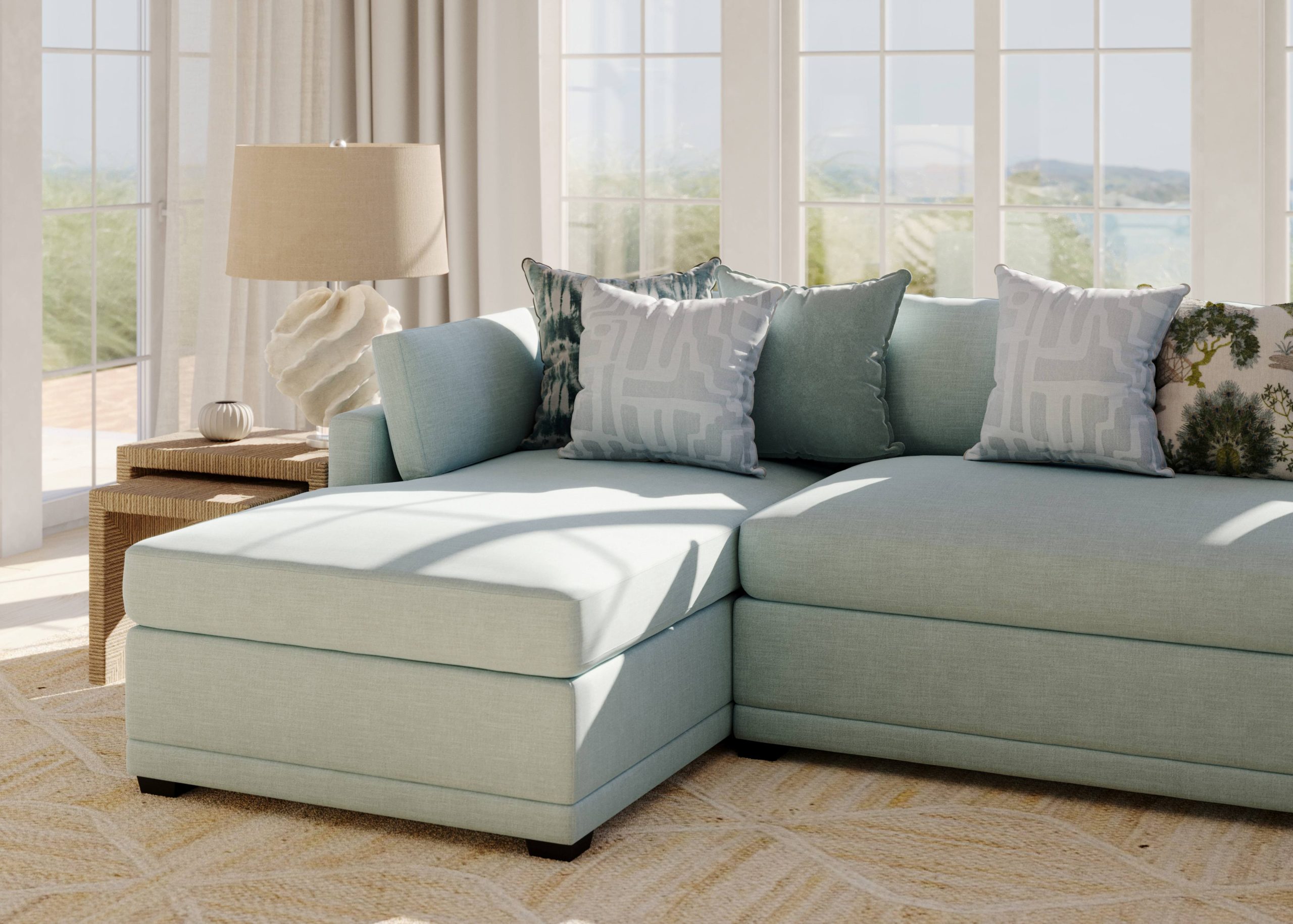 A chaise sectional with blue performance fabric is topped with throw pillows in an elegant coastal living room