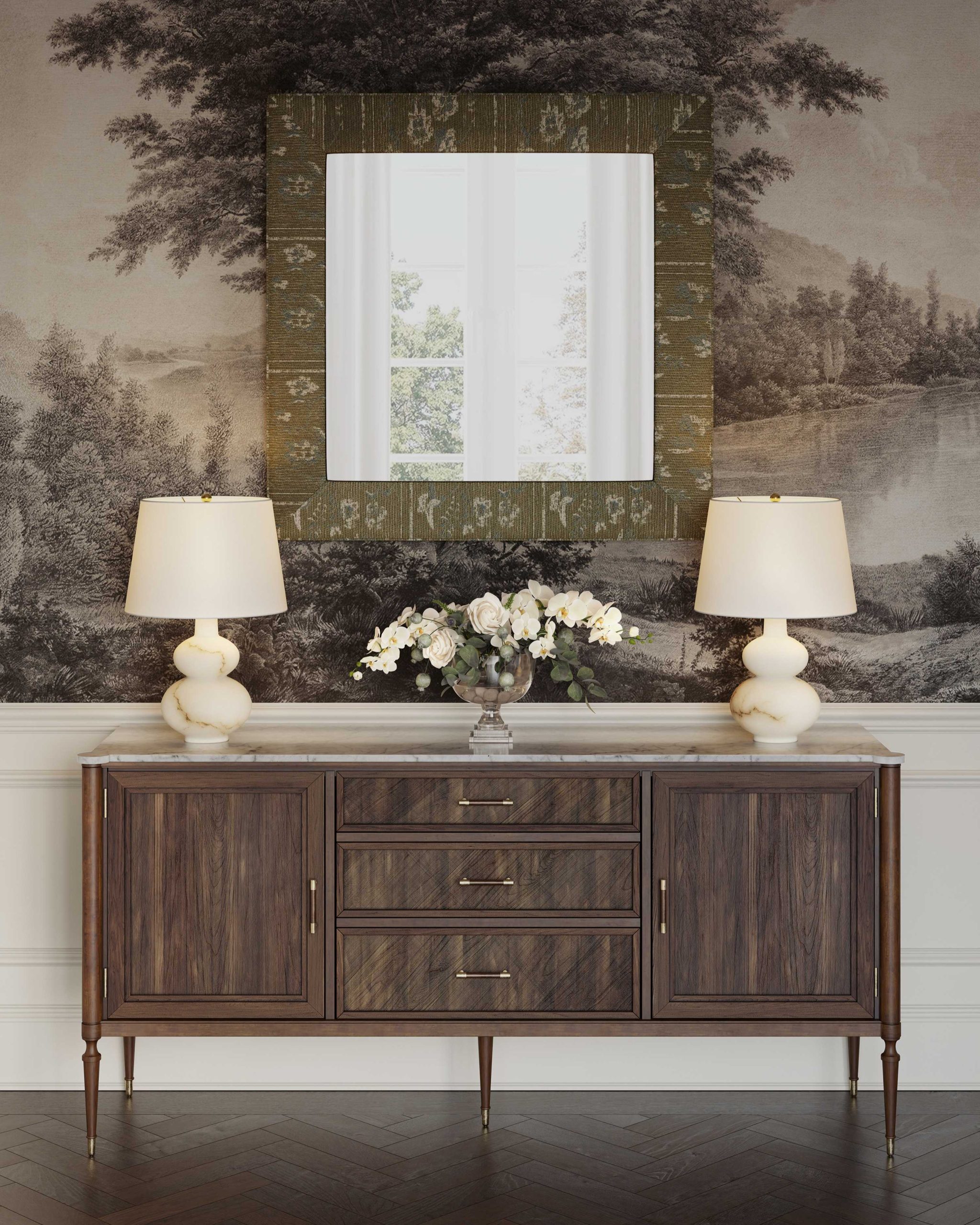 A wood and marble sideboard in a traditional dining room with an upholstered mirror above it