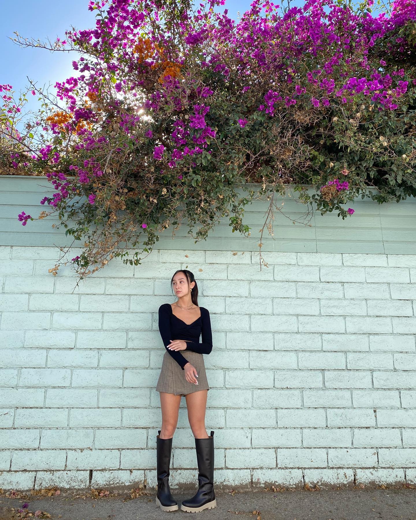 woman standing against brick wall with flowers