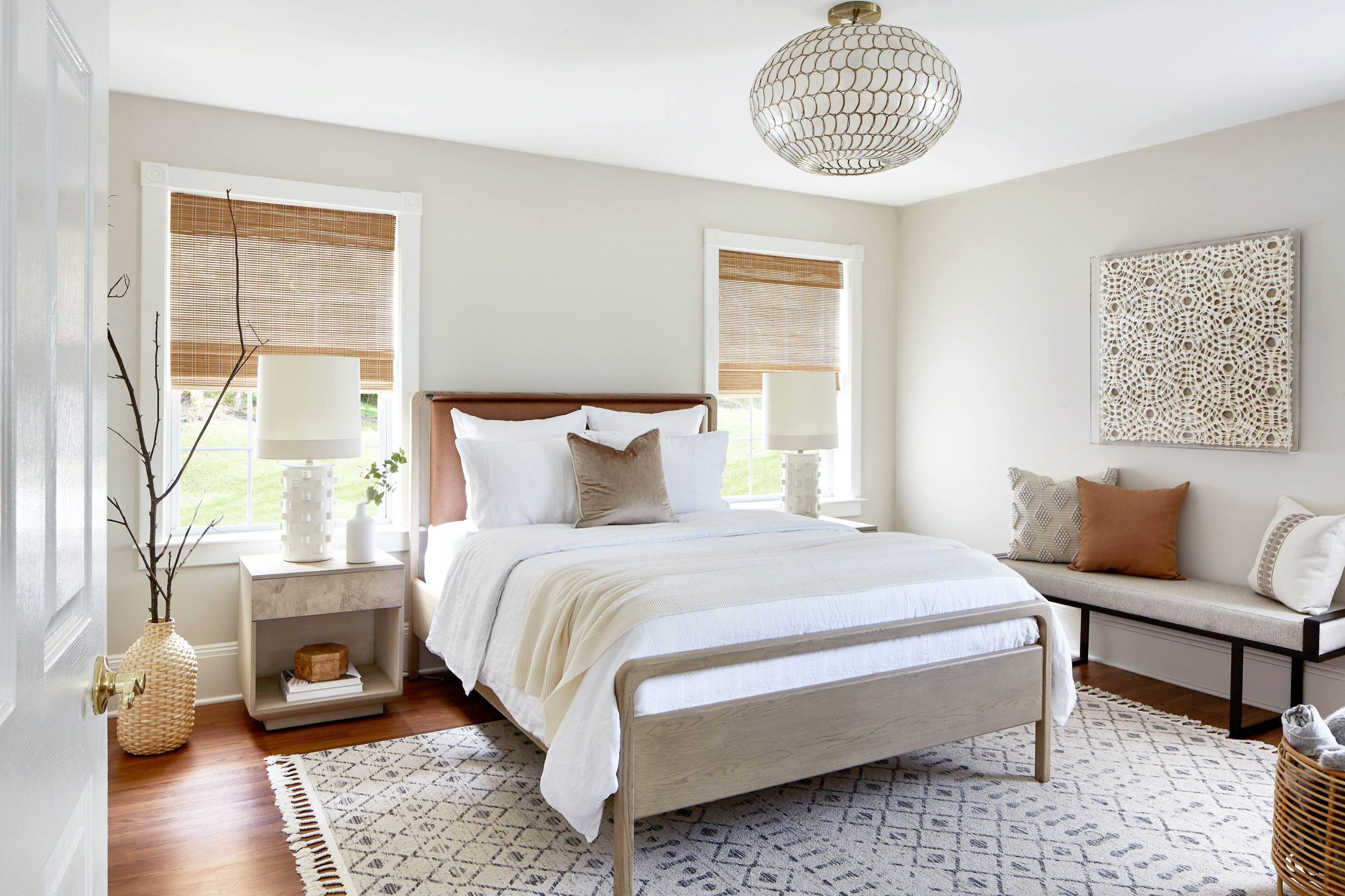 a cozy bedroom with a midcentury-modern bed, diamond-patterned rug, and upholstered bench