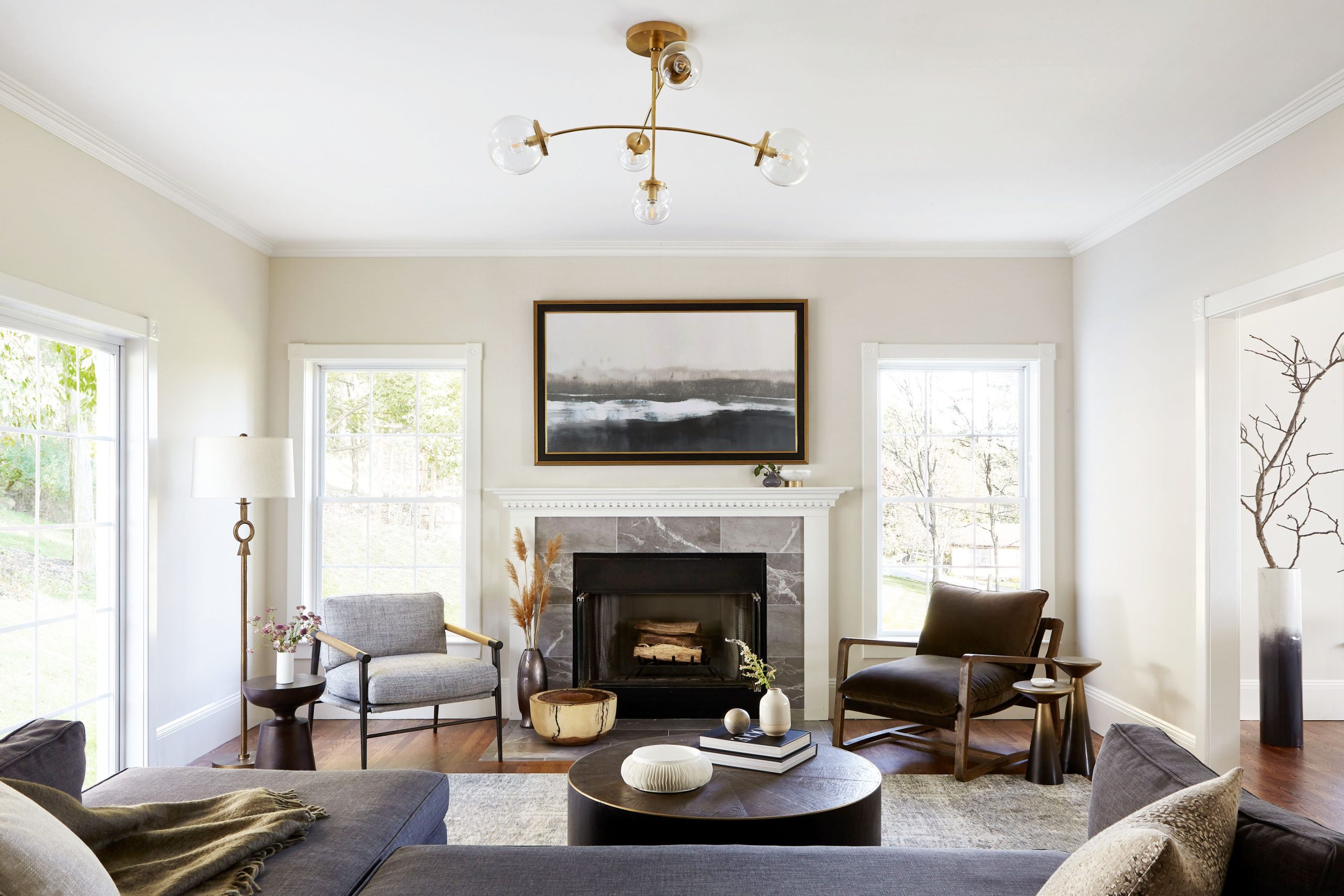a modern farmhouse living room with midcentury modern chairs, a fireplace, and a sputnik light fixture