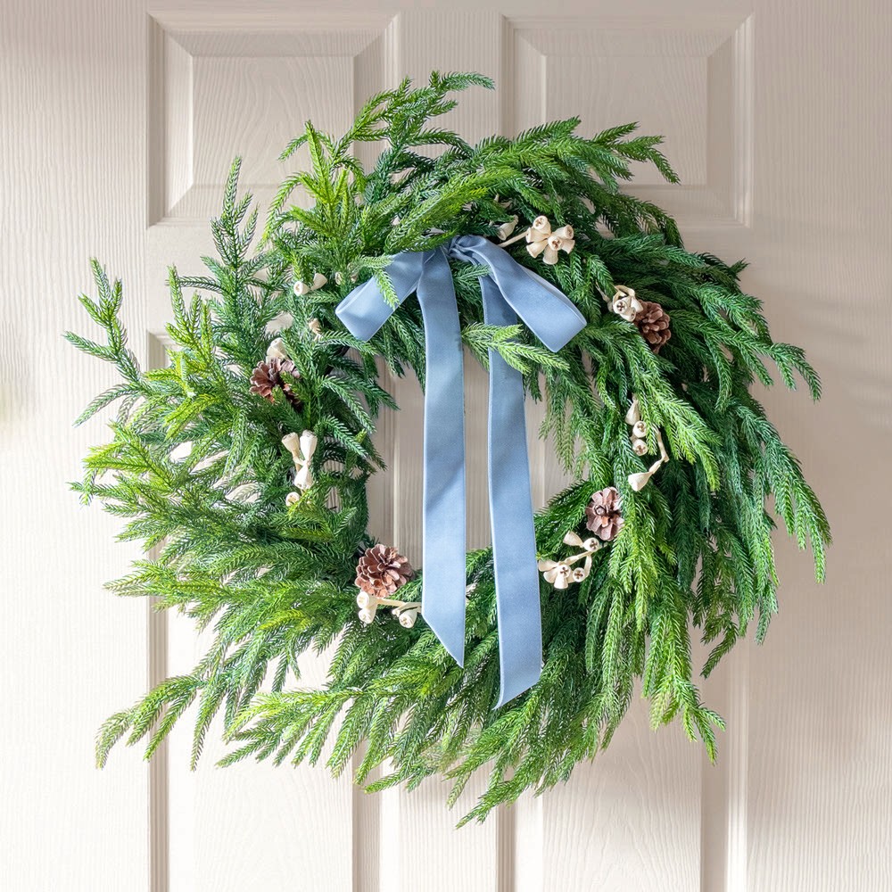 Green pine holiday wreath with pinecones and a blue velvet bow