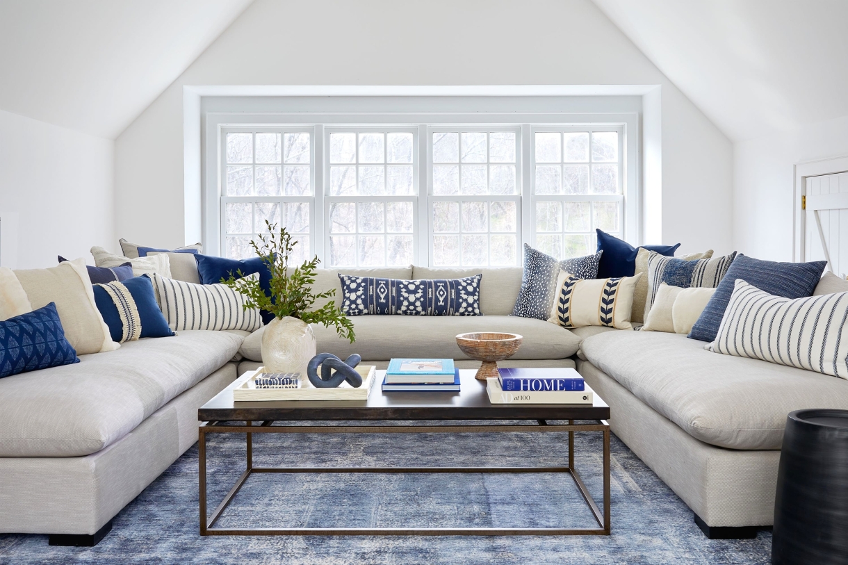 U-Shaped sectional in a family room with layered blue throw pillows and a rectangular wood coffee table