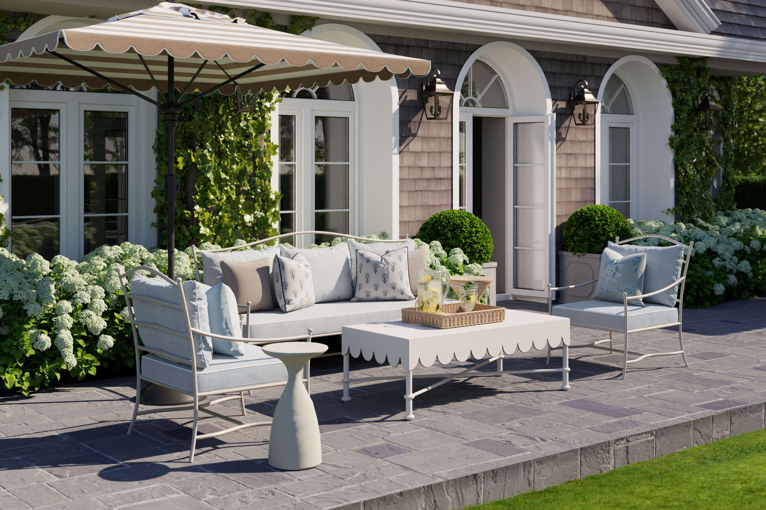 An outdoor living space with a Sunbreall sofa, Sunbrella armchairs, and a scalloped outdoor coffee table