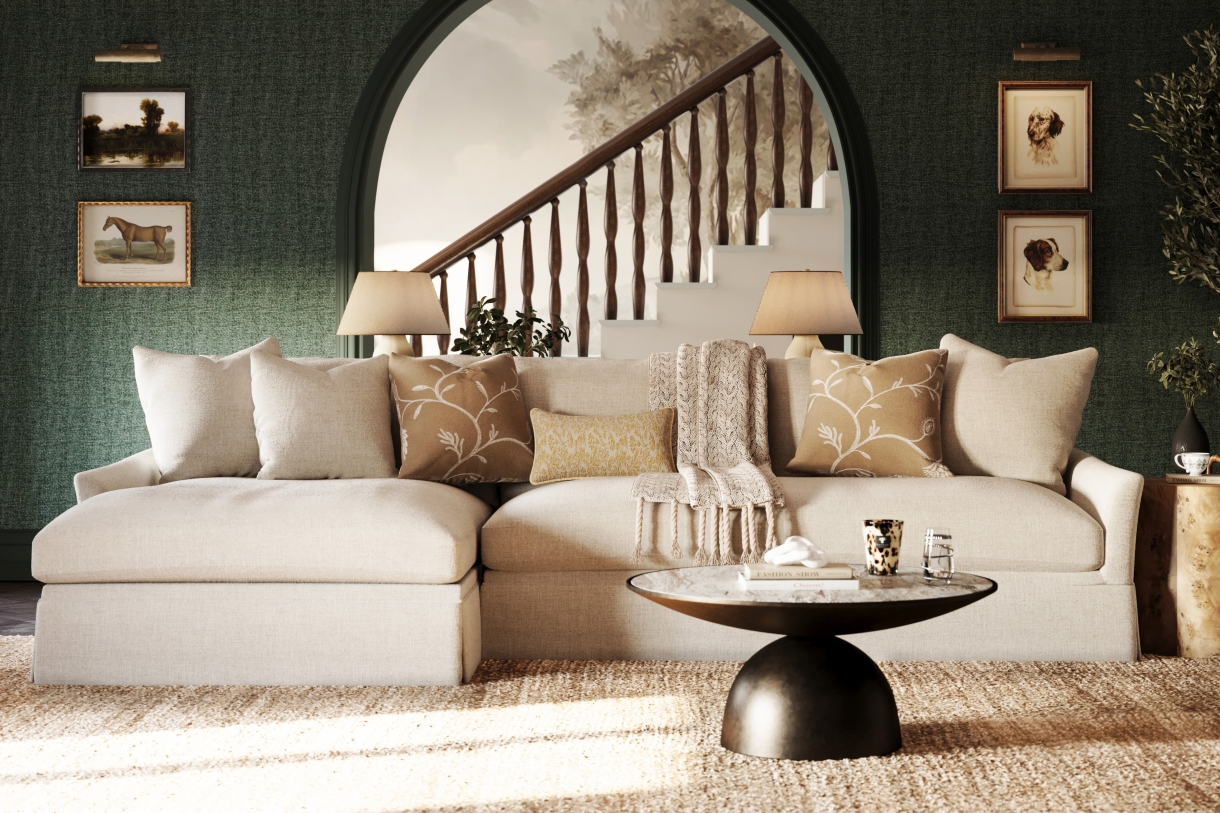 drawing room with chaise sectional, green walls, framed artwork, a round coffee table, and layered throw pillows