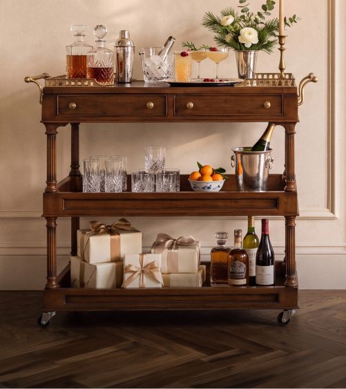 Bar cart stocked with spirits and wrapped gifts