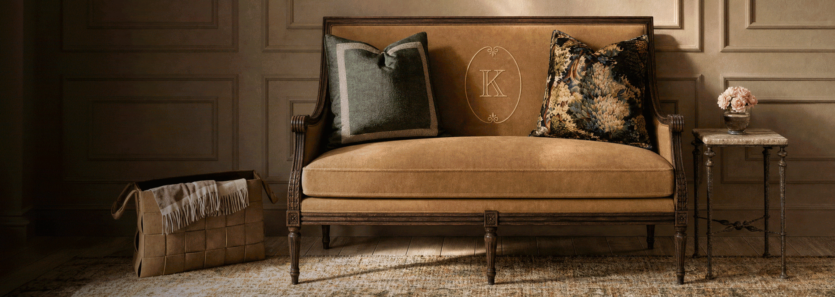 Camel velvet settee with an embroidered monogram and tapestry pillows