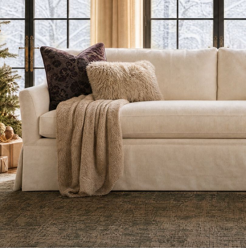 Cream skirted sofa layered with pillows and a knit throw
